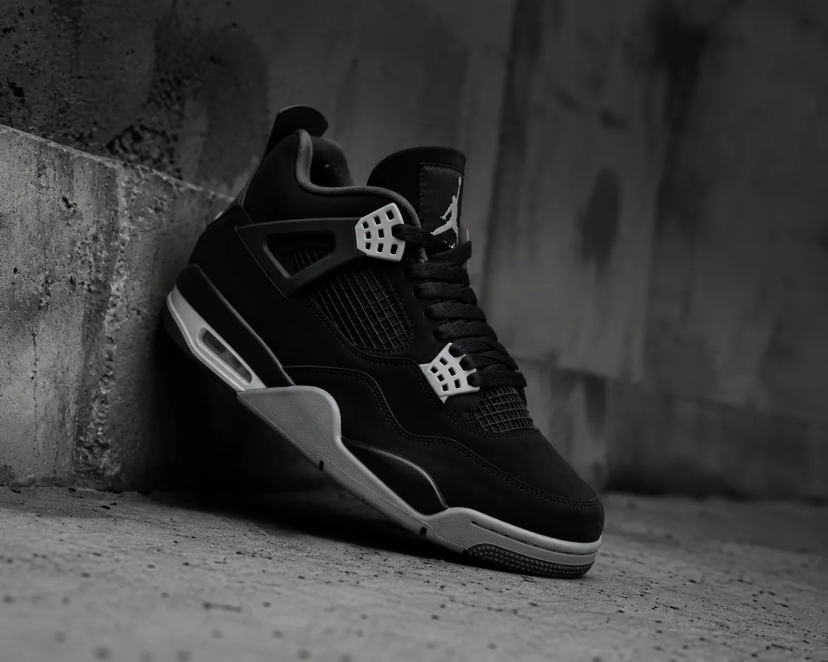 Air Jordan 4 negras apoyadas en una pared de concreto